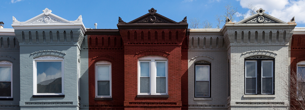 Upper floors and windows of brightly-colored brick townhouses