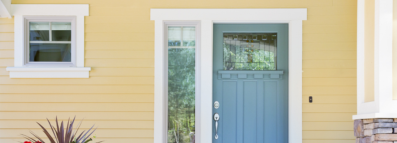 Front of home with potted plant, yellow siding, and a light blue door