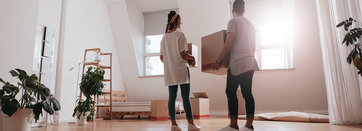 Man and woman in bedroom holding moving boxes