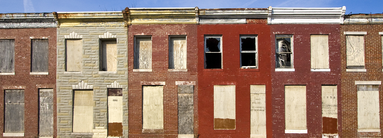 Block of abandoned townhouses with boarded-up windows and doors