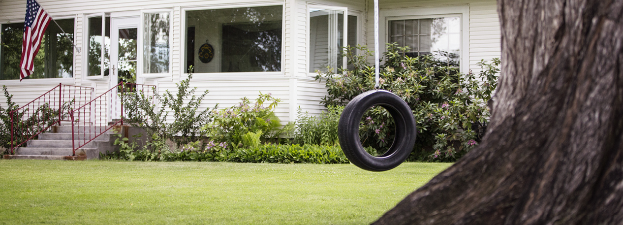 White home with enclosed patio and tire swing hanging from a tree in the yard