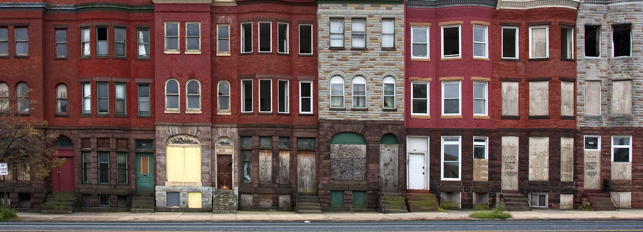 Block of abandoned townhouses with boarded-up windows and doors