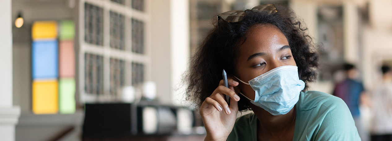 Worried woman with a face mask looking at a laptop.