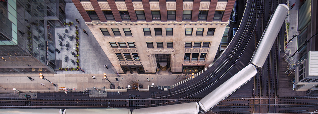 Photo from above of an elevated commuter train rounding a bend around a building