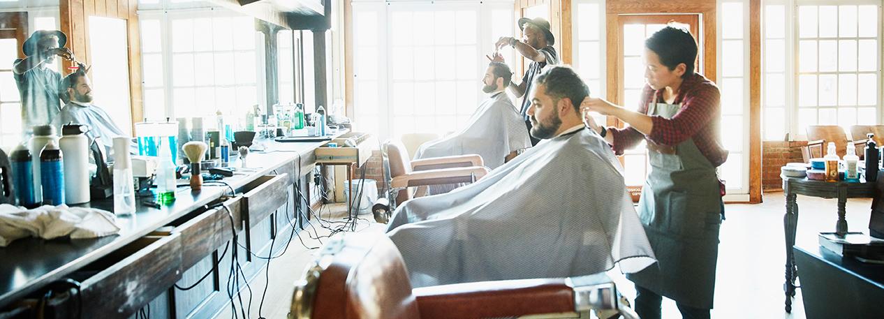 Men sitting in a barber chairs, getting their hair cut