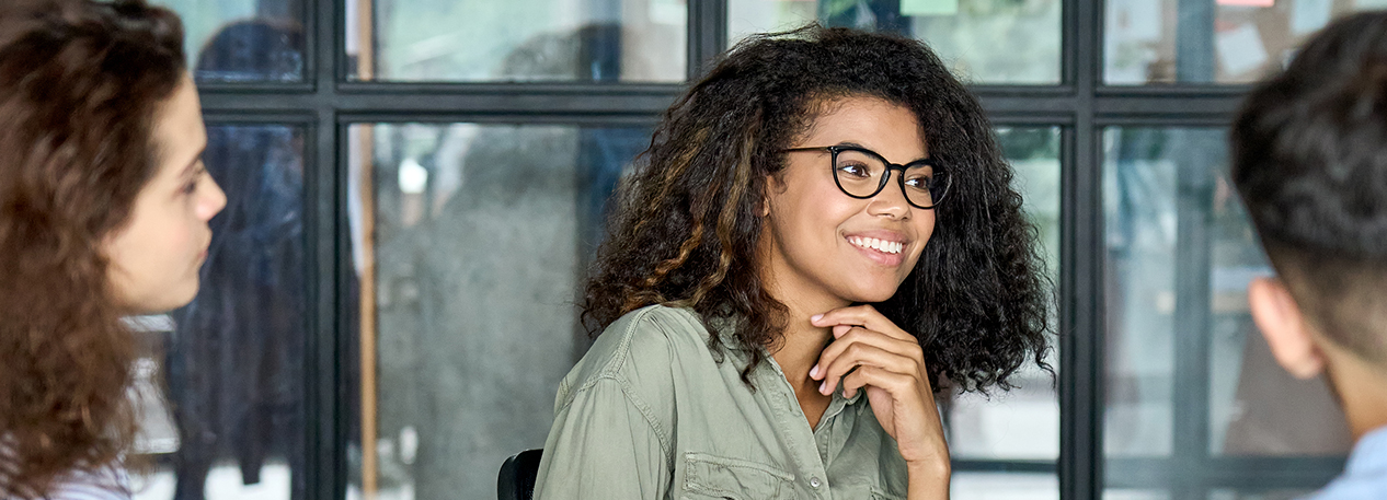 A woman in glasses smiles, and another woman look on.