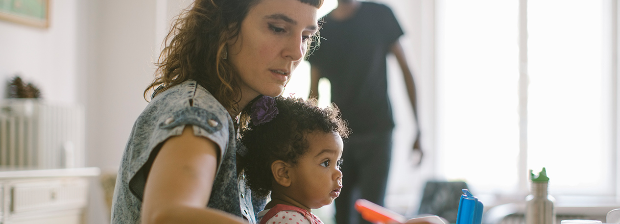 Woman working at a table with her child on her lap