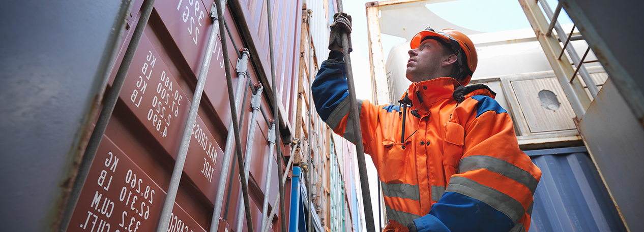 Worker in hardhat standing next to shipping container