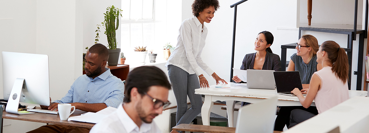 Coworkers interacting and working on computers in a modern office.