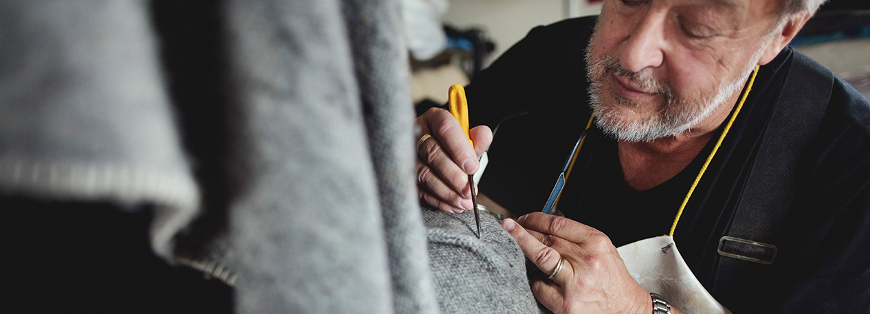 Man in apron working with small tools on a piece of fabric