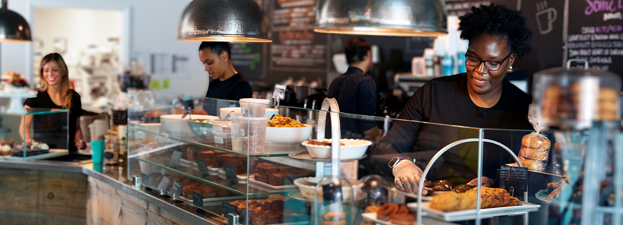 Employees at a cafe work behind the counter.