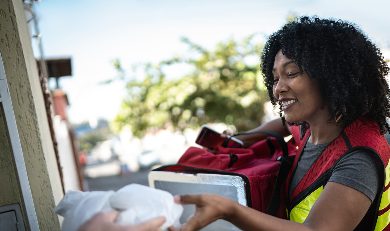 A delivery person hands the customer their food.