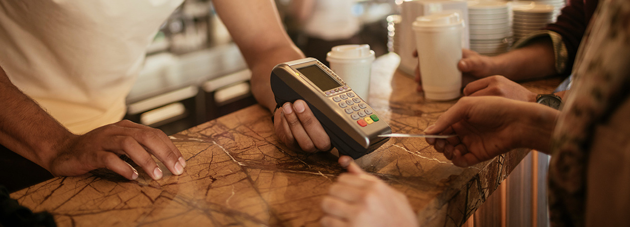 Close-up of person paying at a credit card reader in coffee shop