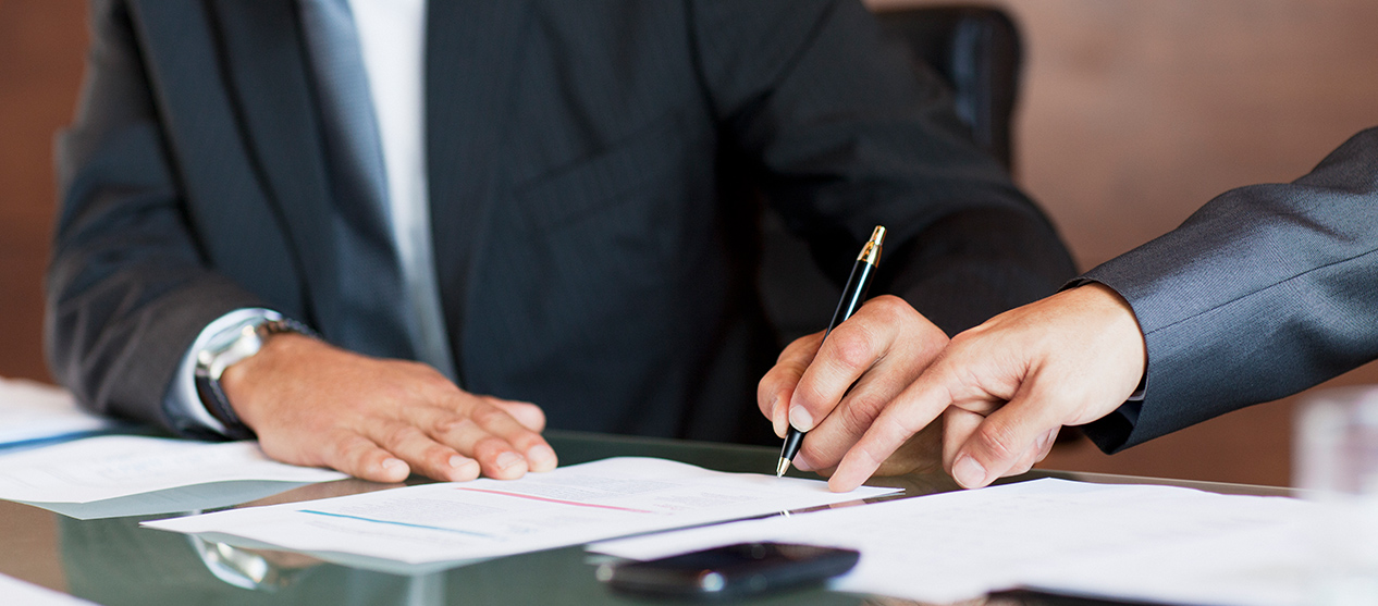 Man in suit signing a document at conference table