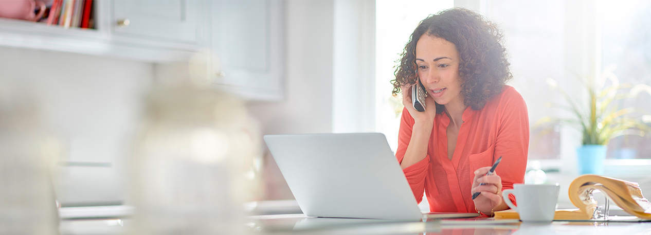 Woman speaking on telephone and looking at laptop computer