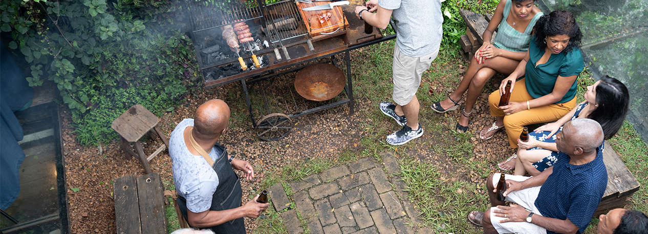 Family sitting around a grill at a backyard gathering