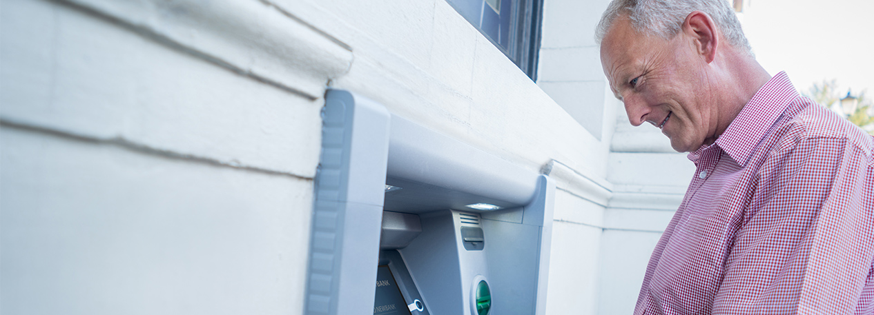 Older man standing at an ATM