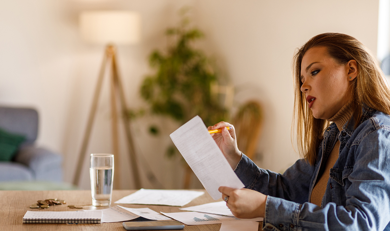 A woman reviews paperwork at the kitchen table.