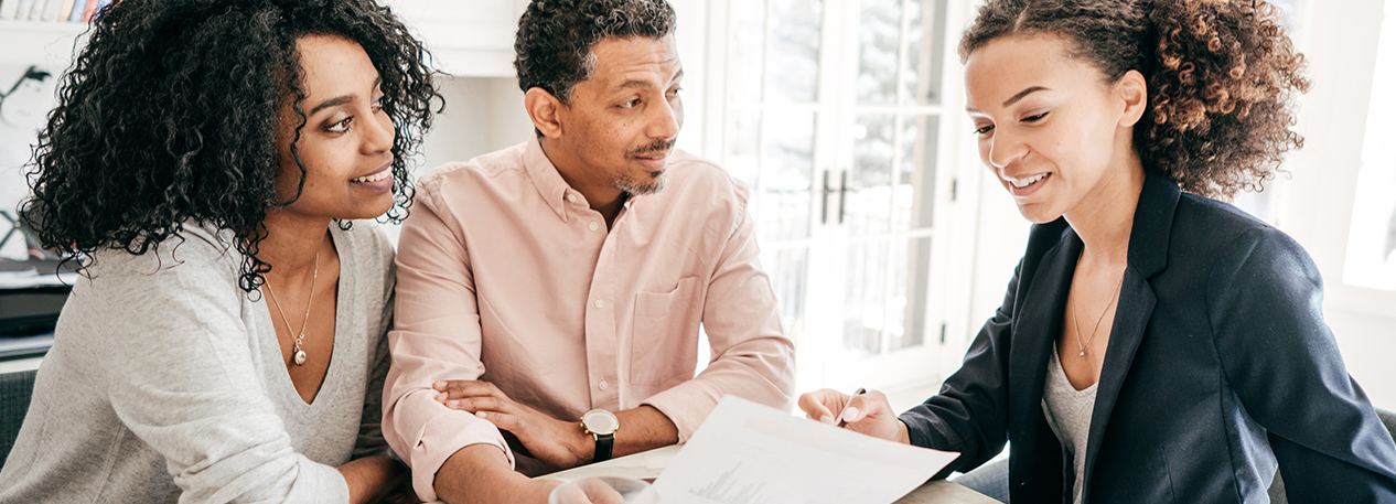 Couple reviewing paper documents with woman in a blazer