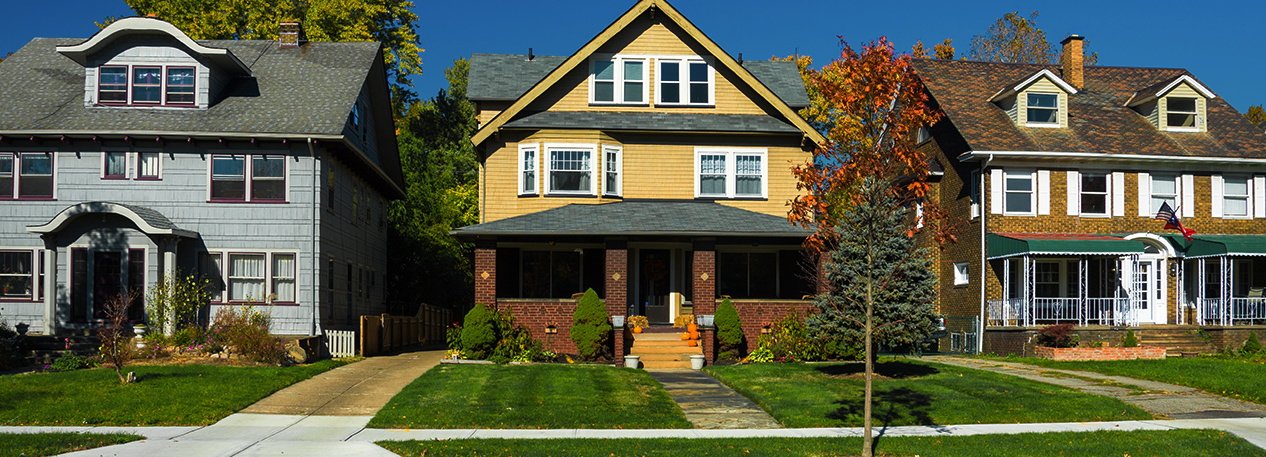 Single family homes along a street, including one decorated with pumpkins on the porch.