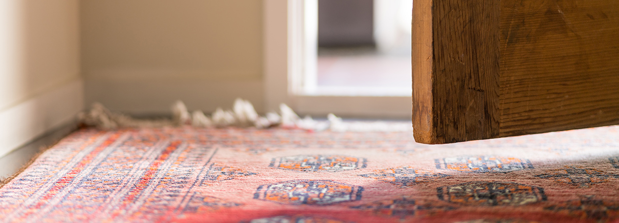 Close-up of a wooden door, ajar, above an area rug