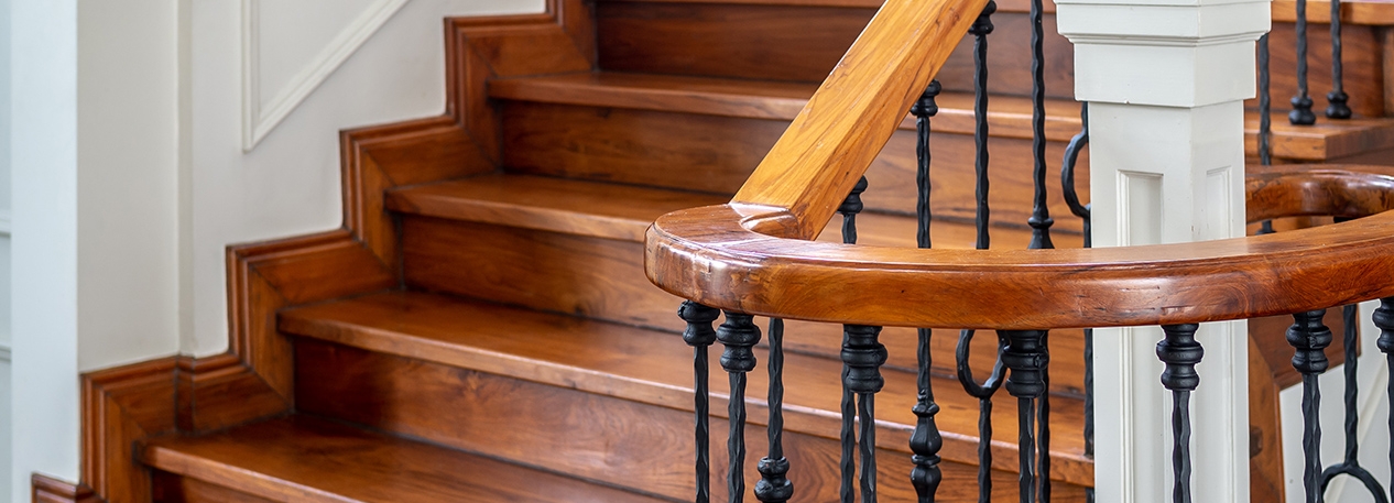 A flight of hardwood stairs and a wrought iron bannister with wooden handrail
