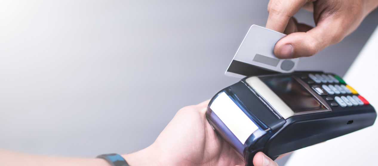 Close-up of a customer swiping a credit card through a hand-held reader