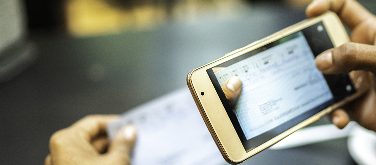 Close-up of hands holding a cellphone and using it to deposit a check