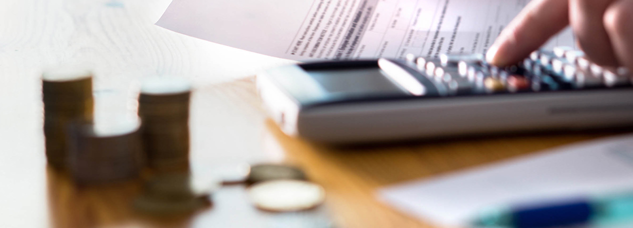 Close-up of desk with one hand holding a paper and another hand using a calculator