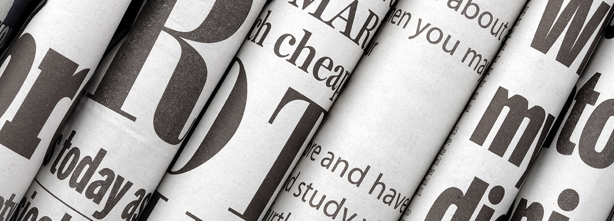 Series of rolled newspapers with various fonts and letters visible