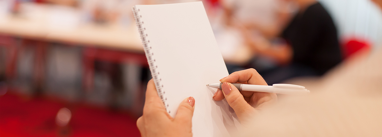 Woman holding a spiral notepad and pen