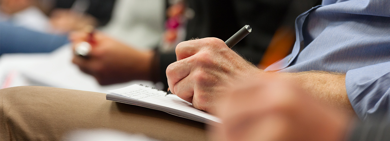 Audience member sitting and writing in a notebook on his lap