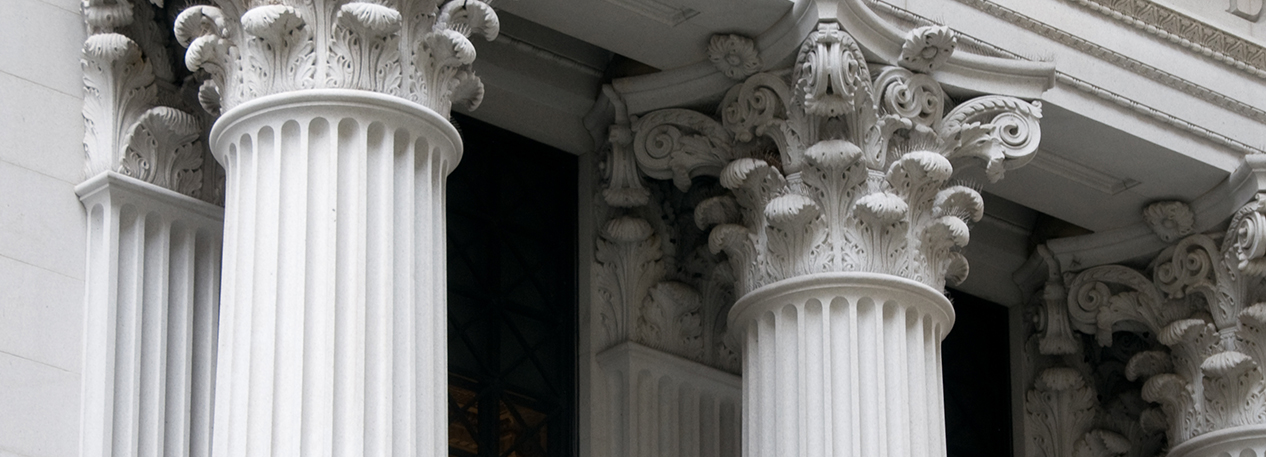 White columns with ornate caps on the outside of a bank building.