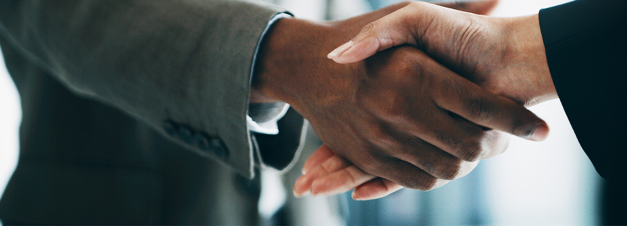 A person wearing a suit shakes the hand of another.