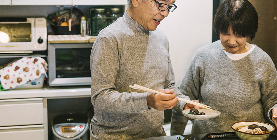 A Japanese couple is preparing a meal in a kitchen.