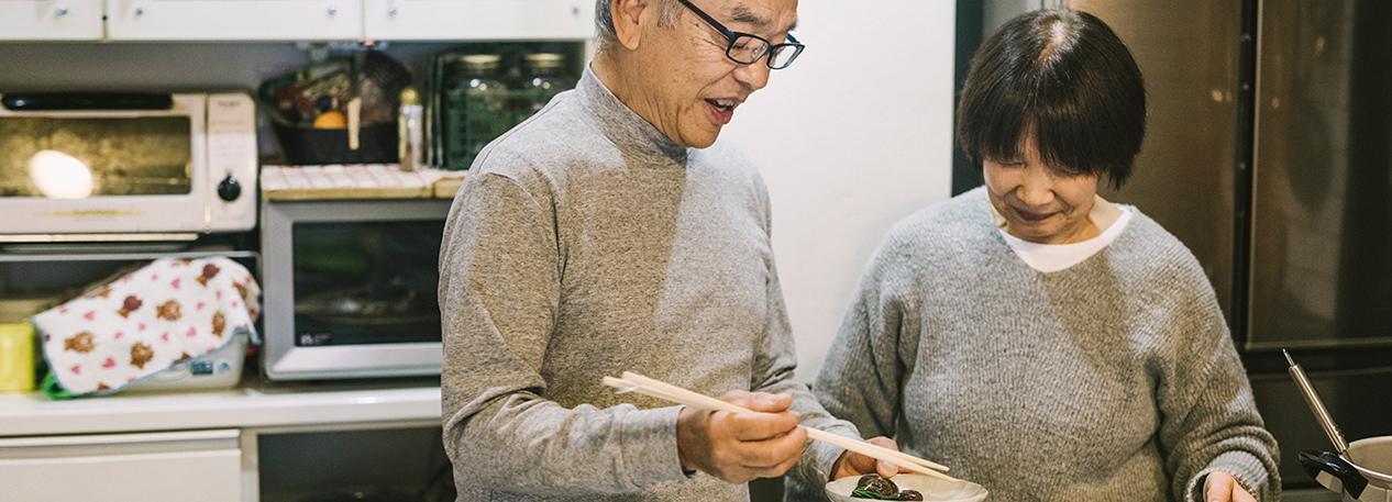 A Japanese couple is preparing a meal in a kitchen.