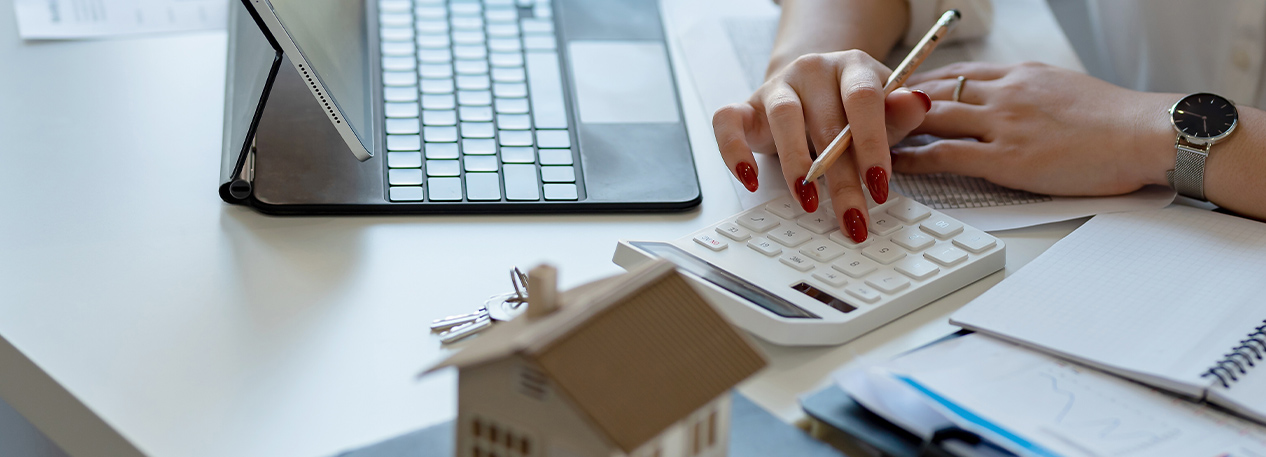A woman at a desk uses a computer and calculator.