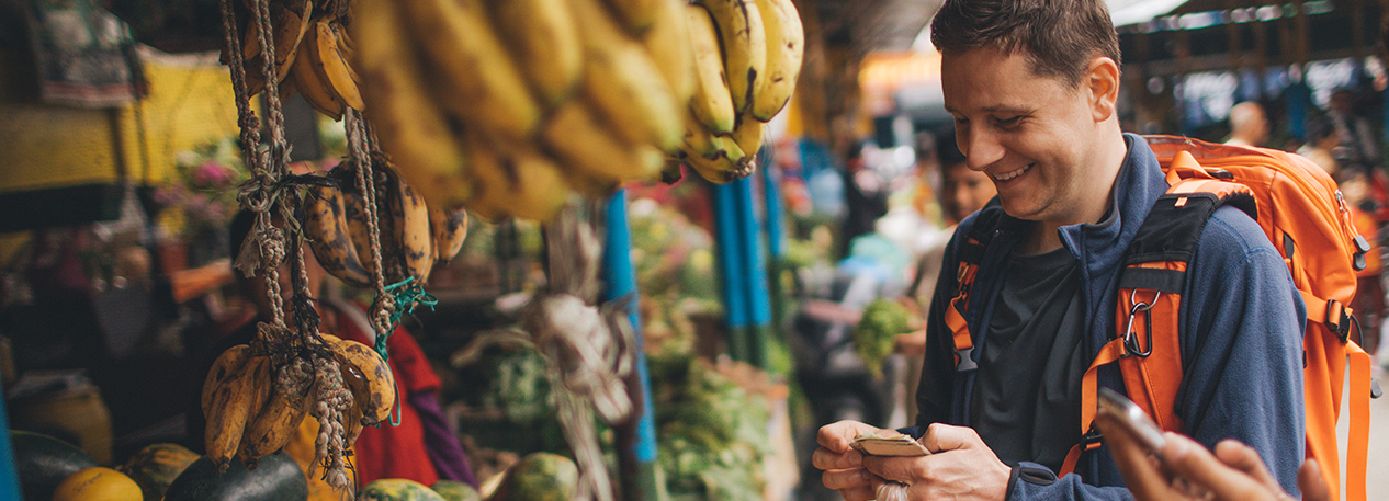 Man with backpack buying fruit and vegetables at a farmers market