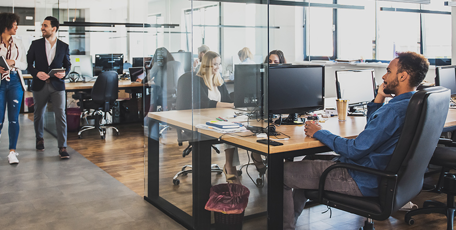 Cubicles and a hallway in a busy modern office.