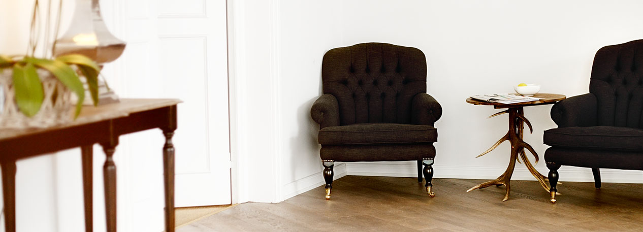 Two dark armchairs and a small table in a room with hardwood floors