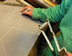 A student at the Trades Learning Center at Bath Iron Works in Bath, ME, determines angles and distances for a map of an enclosed space to plan his electrical equipment needs.