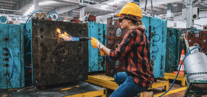 Woman in a hard hat working with a blowtorch.