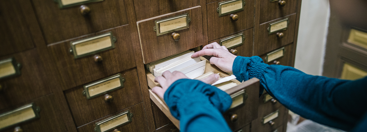 A person flips through files in a filing cabinet.