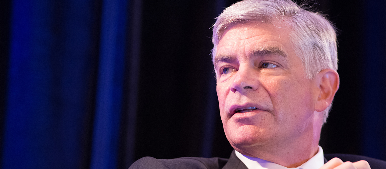 Philadelphia Fed President Harker speaking with stage curtain backdrop