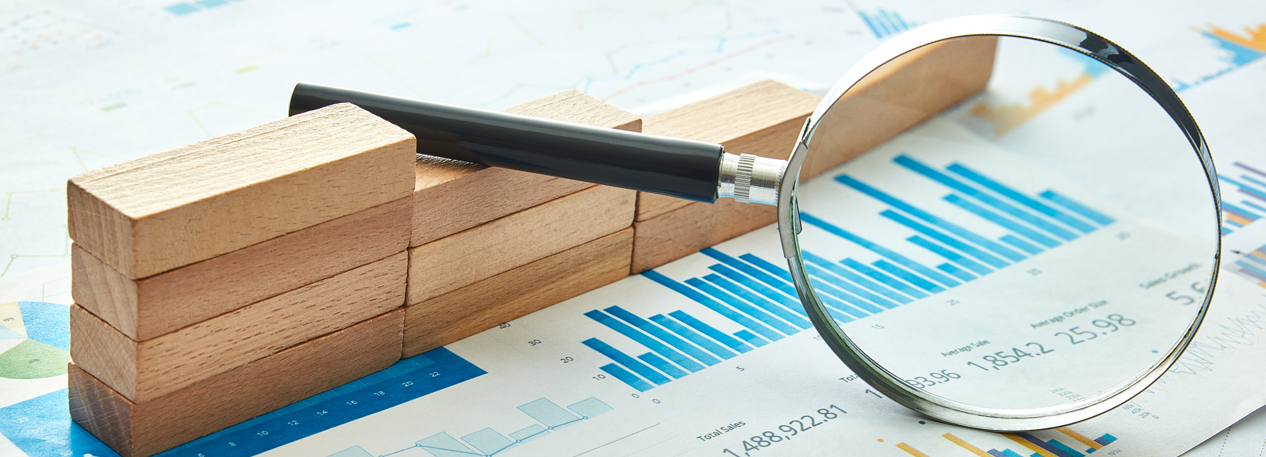 Magnifying glass focusing on a graph figure while propped up by wooden blocks