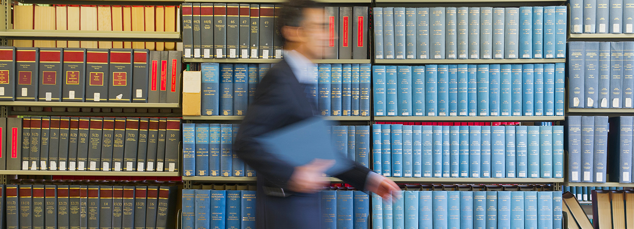 Individual walking past several shelves of books