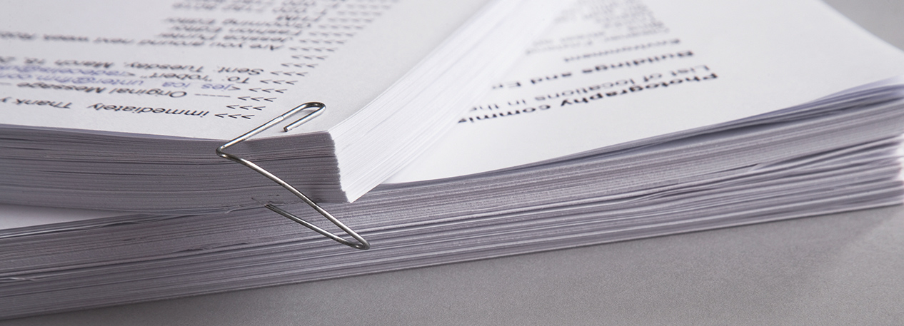 Stacks of papers held together by a paperclip 