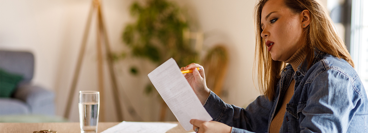 A woman reviews paperwork at the kitchen table.